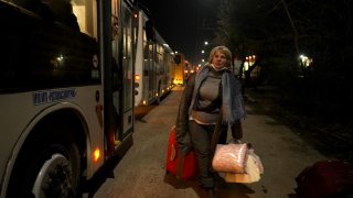 A woman carries her belongings as people evacuated from the self-proclaimed Donetsk People’s Republic sit in a bus waiting to be relocated.