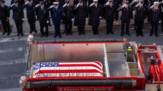 Firefighters salute as the funeral procession leaves the memorial service for three fallen Baltimore City Fire Department firefighters at the Baltimore Convention Center on Feb. 2, 2022. Lt. Paul Butrim, Lt. Kelsey Saddler and EMT/firefighter Kenny Lacayo were killed when a vacant house collapsed during a fire in West Baltimore last week.