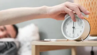 Image of a man turning off an alarm clock.