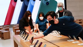 An employee arranges Apple iPhones as customer shop at the Apple Store on 5th Avenue shortly after new products went on sale in Manhattan, in New York City, March 18, 2022.