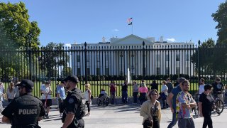 Police officers and tourists standing outside the White House Sept. 26, 2021.