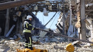 A rescue worker gestures in front of the shopping and entertainment center in the Ukrainian Black Sea city of Odessa on May 10, 2022, destroyed after Russian missiles strike late on May 9, 2022.