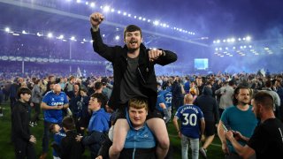 Everton fans celebrate on the pitch following their sides victory