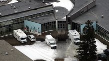 Police and investigators' vehicles are parked in front of the Red Lake Senior High School