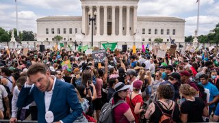 A journalist reports near a crowd of abortion-rights activists in front of the U.S. Supreme Court after the Court announced a ruling in the Dobbs v Jackson Women’s Health Organization case on June 24, 2022 in Washington, DC.