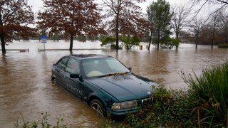 A car sits semi-submerged in flood waters