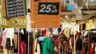 A shopper wearing a protective face mask walks inside the Urban Outfitters retail store during Black Friday sales at Roosevelt Field shopping mall in Garden City, New York, November 26, 2021.