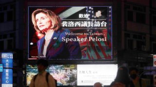 People walk past a billboard welcoming U.S. House Speaker Nancy Pelosi, in Taipei, Taiwan, Tuesday, Aug 2, 2022.