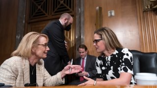 Sen. Maggie Hassan, D-N.H., left, speaks with Sen. Kyrsten Sinema, D-Ariz., during a meeting of the Senate Homeland Security Committee at the Capitol in Washington, Wednesday, Aug. 3, 2022.