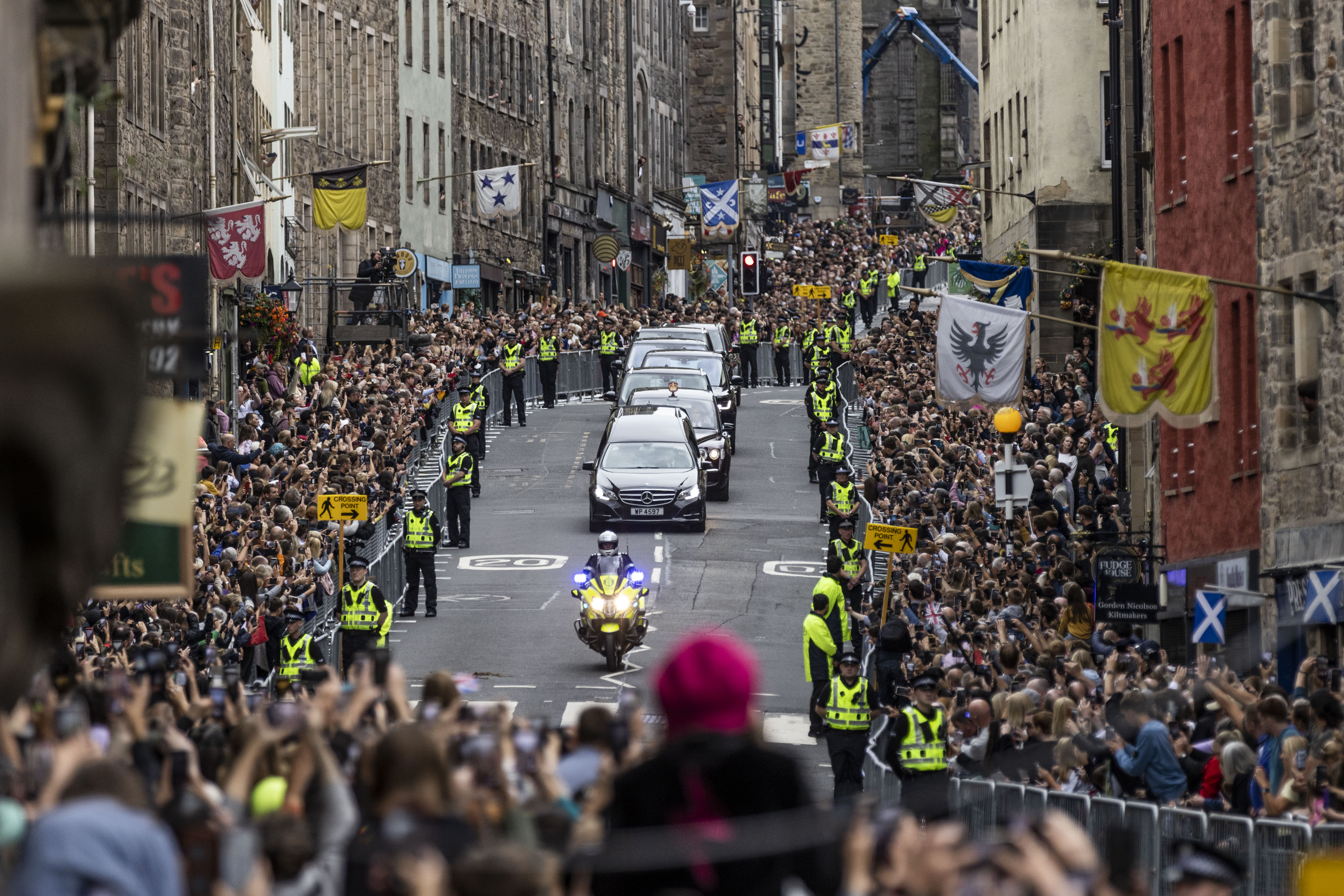 People gather on the Royal Mile, Edinburgh, Scotland, to watch the cortege carrying the coffin of the late Queen Elizabeth II, draped with the Royal Standard of Scotland, as it completes its journey from Balmoral to the Palace of Holyroodhouse, Sept. 11, 2022.