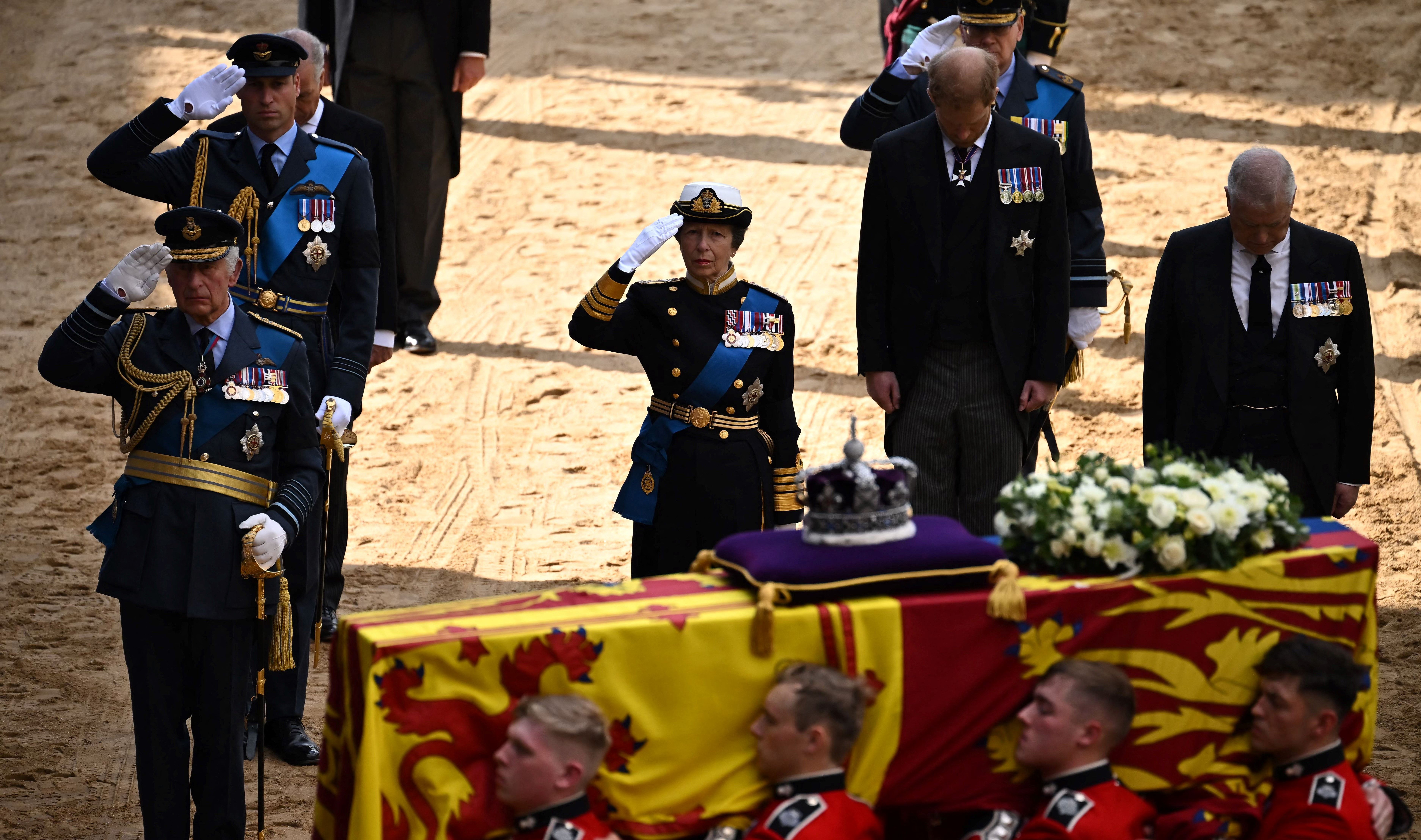 King Charles III, Prince William, Prince of Wales and Princess Anne, Princess Royal salute the coffin of Queen Elizabeth II, adorned with a Royal Standard and the Imperial State Crown, as it arrives at the Palace of Westminster, Sept. 14, 2022, in London. Next to them is Prince Harry, Duke of Sussex, and Prince Andrew, Duke of York.