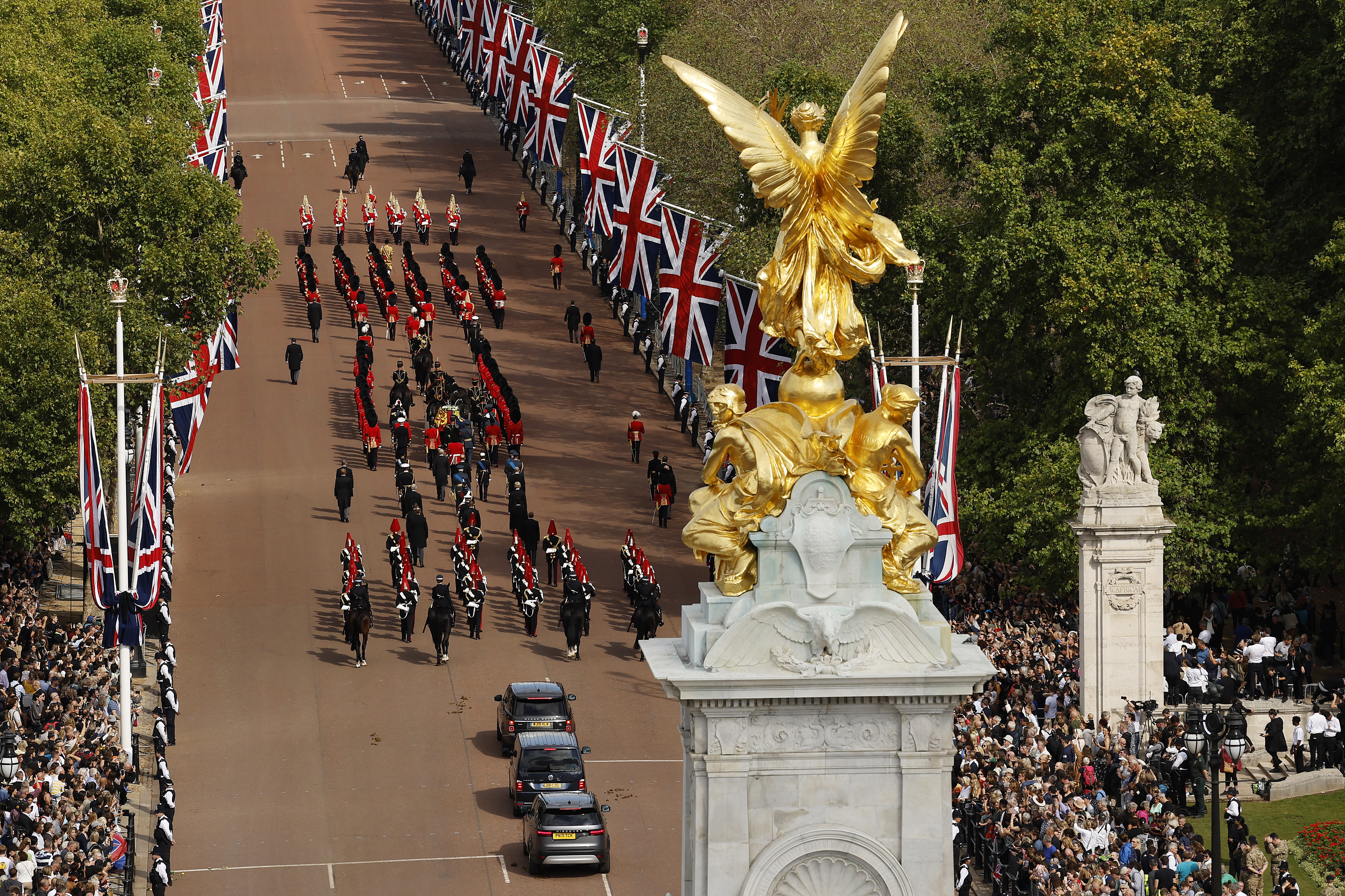 Members of the public line the Queen Victoria Memorial and the Mall as King Charles III and members of the royal family walk with Queen Elizabeth II’s flag-draped coffin as it is taken in procession by The King’s Troop Royal Horse Artillery from Buckingham Palace to Westminster Hall, Sept. 14, 2022 in London.