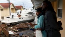 Frankie Romulus (left) and Kendrick Romulus (right) stand outside of their apartment next to a boat that floated into their apartment complex when Hurricane Ian passed through the area on September 29, 2022 in Fort Myers, Florida.