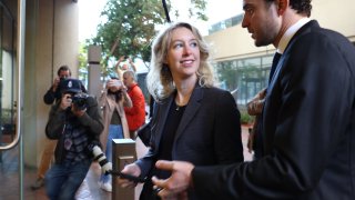 Former Theranos CEO Elizabeth Holmes (L) arrives at federal court with her partner Billy Evans on October 17, 2022 in San Jose, California.