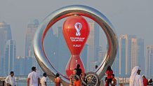 A picture taken on October 20, 2022, shows people walking past the Qatar 2022 FIFA World Cup countdown clock as it nears marking thirty days, in the Qatari capital Doha. (Photo by Karim JAAFAR / AFP) (Photo by KARIM JAAFAR/AFP via Getty Images)