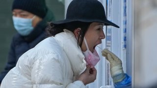 A woman has her routine COVID-19 throat swab at a coronavirus testing site in Beijing, Sunday, Dec. 4, 2022.
