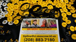 A flyer seeking information about the killings of four University of Idaho students who were found dead is displayed on a table along with buttons and bracelets