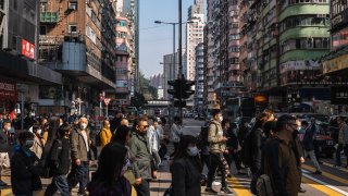Pedestrians cross a street in Mong Kok district in Hong Kong, after officials announced measures for the city to end some of its last major Covid rules, scrapping gathering limits to vaccination checks and testing for travelers. Photographer: Lam Yik/Bloomberg via Getty Images
