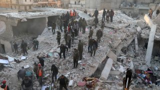 In this photo provided by Kurdish-run Hawar News Agency, civil defense workers and civilians work on the rubble of a destroyed building in the Sheikh Maksoud neighborhood in Aleppo, Syria, Sunday, Jan. 22, 2023.