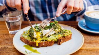 Man eating avocado toast with poached egg, close up