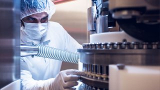 Novartis manufacturing associate checking punches at compressing machine.
