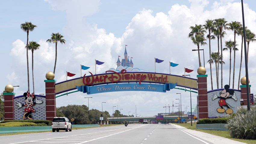 Cars drive under a sign greeting visitors near the entrance to Walt Disney World, July 2, 2020, in Lake Buena Vista, Fla.