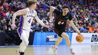 Jordan Wood of the Howard Bison drives to the basket while facing pressure from Gradey Dick of the Kansas Jayhawks.