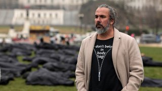 FILE - Activist Manuel Oliver listens during a news conference with reporters at an installation of body bags assembled on the National Mall by gun control activist group March For Our Lives on March 24, 2022, in Washington, D.C.