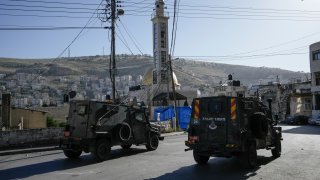 A convoy of Israeli military vehicles drives through the West Bank city of Nablus, during a raid.