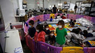 Young unaccompanied migrants, ages 3-9 watch TV inside a playpen at the Department of Homeland Security holding facility on March 30, 2021 in Donna, Texas.