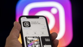 The logo of Threads is displayed on a mobile phone screen in front of a computer screen displaying the logo of Instagram in Ankara, Turkiye on July 04, 2023.Β
