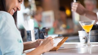 Woman signing receipt after paying bar tab in restaurant