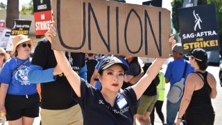 A woman holds a “Union” sign as members of the Writers Guild of America and the Screen Actors Guild walk a picket line outside Paramount Studios in Los Angeles, July 14, 2023.