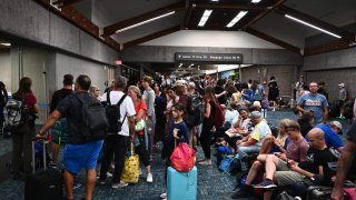 Passengers try to rest and sleep after canceled and delayed flights while others wait to board flights off the island as thousands of passengers were stranded at the Kahului Airport (OGG) in the aftermath of wildfires in western Maui in Kahului, Hawaii on August 9, 2023. 