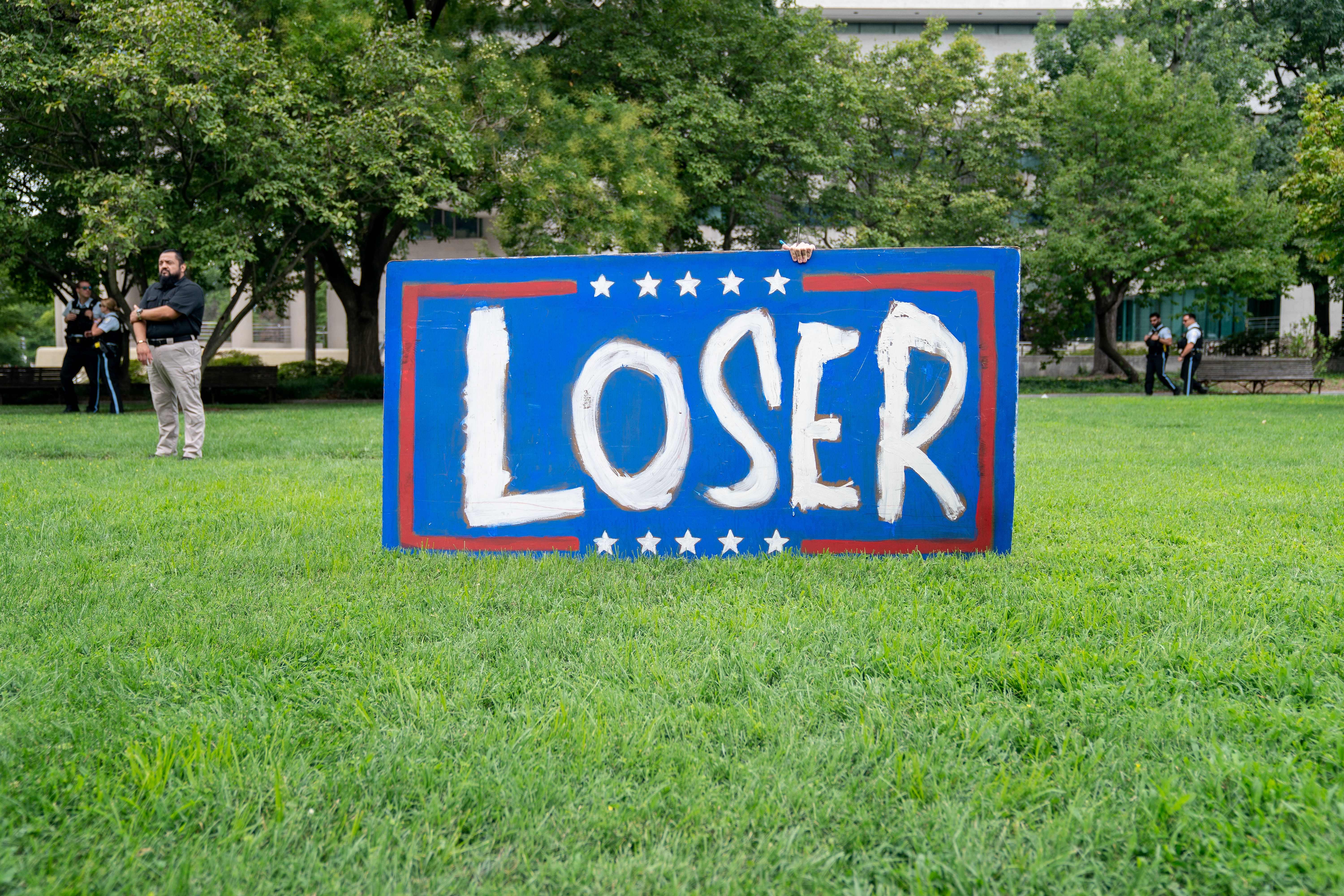 A demonstrator stands next to a sign outside the E. Barrett Prettyman US Courthouse in Washington, DC, on August 3, 2023, ahead of the arraignment of former US President Donald Trump. Trump was indicted on August 1, 2023 over his efforts to overturn the results of the 2020 election — the most serious legal threat yet to the former president as he campaigns to return to the White House. Federal prosecutors allege that Trump enlisted six co-conspirators to “assist him in his criminal efforts to overturn the legitimate results of the 2020 presidential election and retain power.” The co-conspirators are not named in the indictment, but five of them can be identified using the detailed descriptions provided by prosecutors. (Photo by Stefani Reynolds / AFP) (Photo by STEFANI REYNOLDS/AFP via Getty Images)