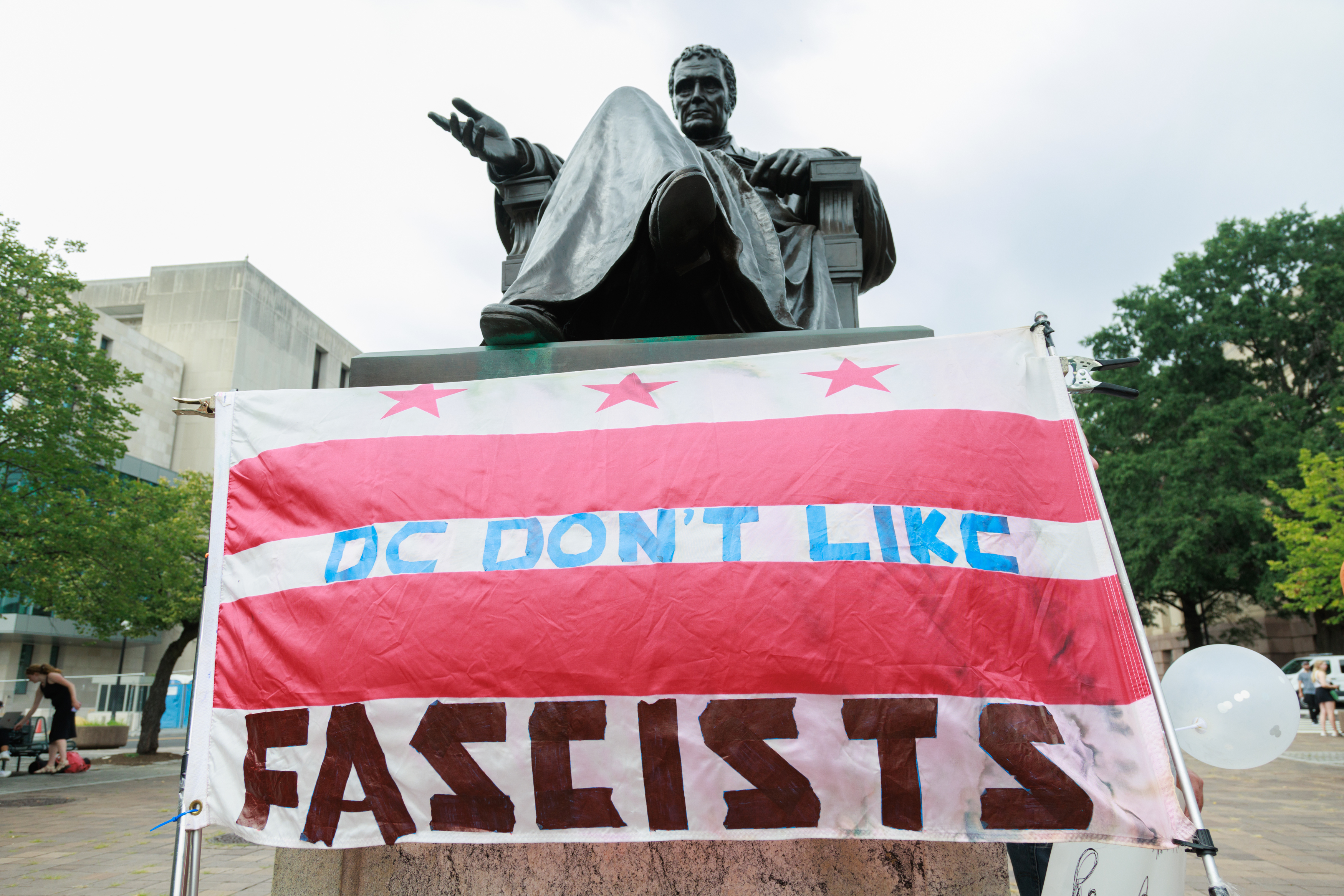 WASHINGTON DC, UNITED STATES – AUGUST 03: A sign reading ‘CD don’t like fascists’ rests against a statue outside of the Elijah Barrett Prettyman Federal Courthouse as anti-Trump and pro-Trump groups stage demonstrations ahead of former US President Donald Trump’s arrival in Washington D.C., United States on August 3, 2023. Former US President Donald Trump was indicated for arraignment on conspiracy and obstruction federal charges related to the January 6, 2021 US Capitol riots. (Photo by Bryan Dozier/Anadolu Agency via Getty Images)