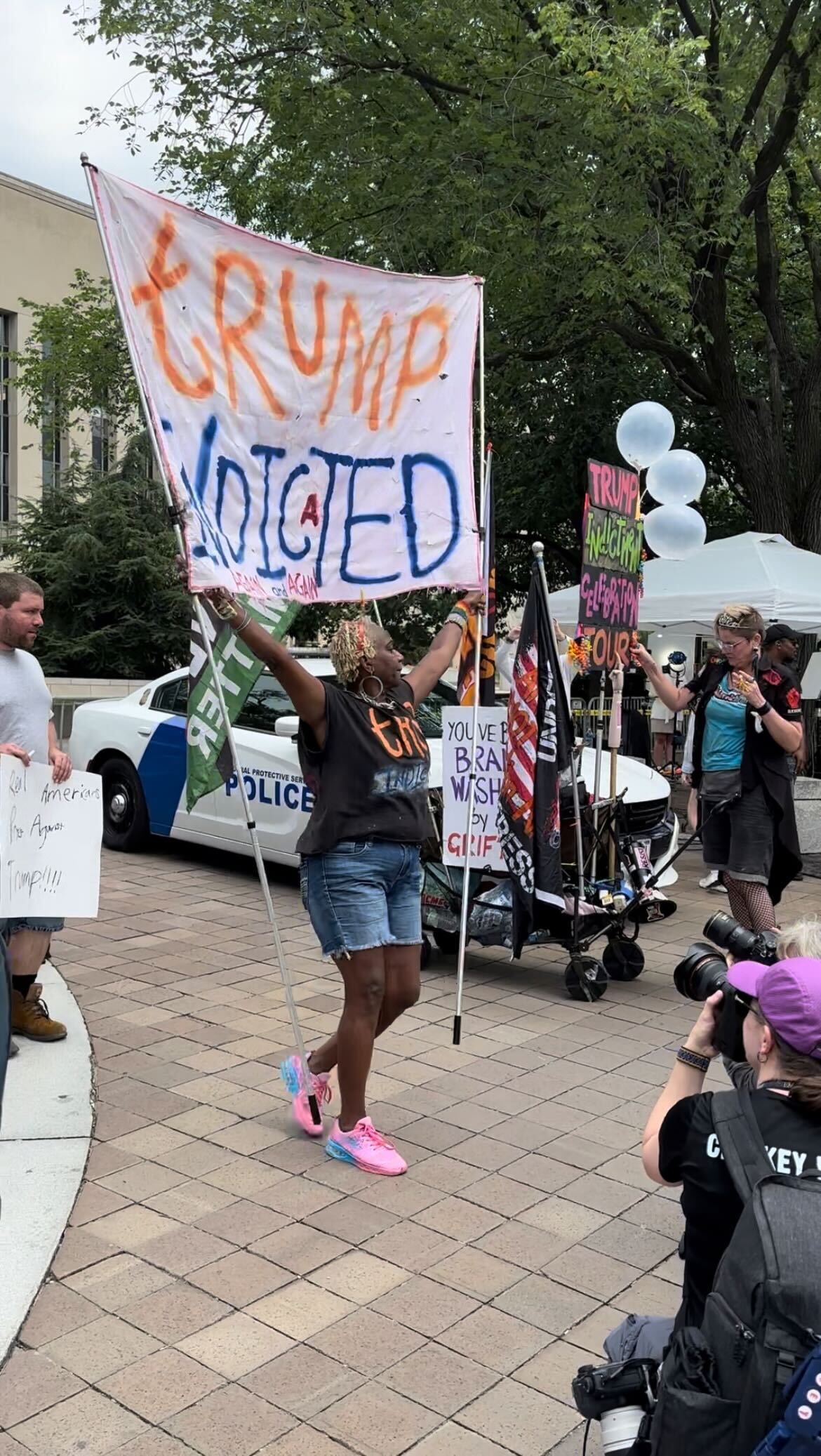 An anti-Trump protestor dances to “Celebration” by Kool & the Gang in front of the courthouse where Trump was arraigned on charges related to election interference.