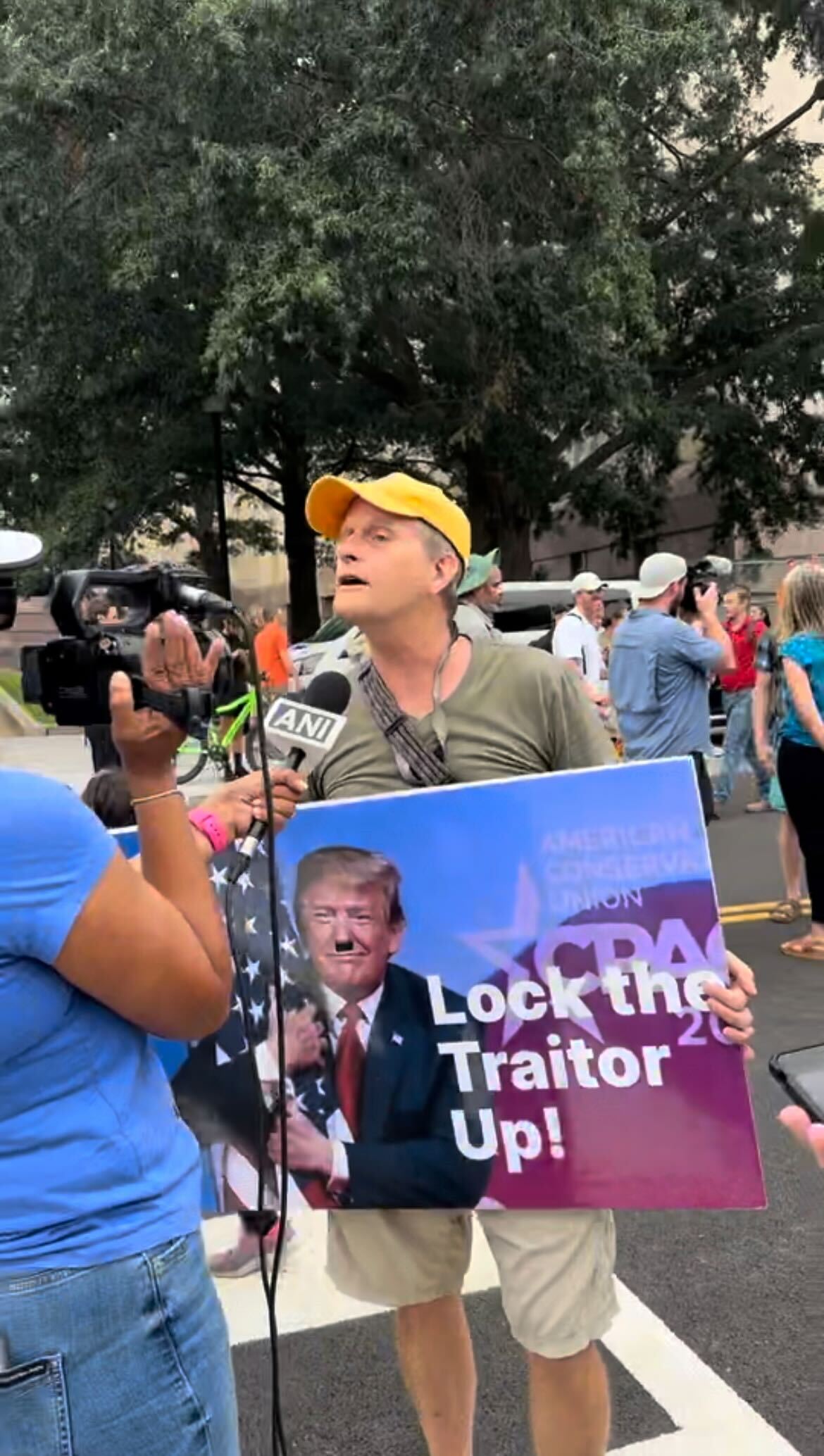 An anti-Trump protestor holds up a sign that reads “Lock the traitor up” while talking to a reporter. Large crowds of spectators and protestors swarmed outside the courthouse where former President Donald Trump was arraigned on charges of election interference.