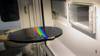 A robotic arm moves 300 mm silicon semiconductor wafers inside a sorting machine in a cleanroom at a Globalfoundries Inc. semiconductor fabrication plant.