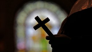 FILE – This Dec. 1, 2012 file photo shows a silhouette of a crucifix and a stained glass window inside a Catholic Church in New Orleans.