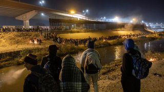 FILE - Venezuelan immigrants look towards hundreds of other migrants who had surged across the Rio Grande into El Paso, Texas