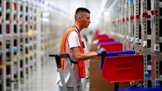 An employee looks for items in one of the corridors at an Amazon warehouse.