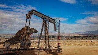 A lone pumpjack located in the middle of a large solar array outside of Bakersfield, Kern County, California.