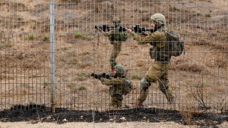 Israeli soldiers scan an area while sirens sound as rockets from Gaza are launched towards Israel,, near Sderot, southern Israel, October 9, 2023. 