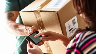 Courier handing over package asking female customer to do electronic signature, delivering, receiving, efficiency