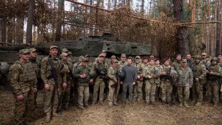 In this photo provided by the Ukrainian Presidential Press Office, Ukrainian President Volodymyr Zelenskyy, center, poses for photo with the Ukrainian soldiers in front of a Leopard 2 tank on the front line in the Kharkiv region, Ukraine, Tuesday, Oct. 3, 2023.