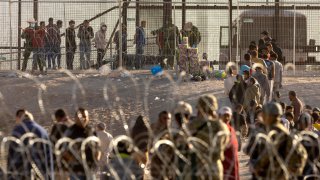 FILE - Immigrants wait to be transported and processed by U.S. Border Patrol