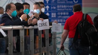 People wearing face masks wait at the international passenger arrivals area at Beijing Capital Inernational Airport in Beijing, on March 15, 2023.