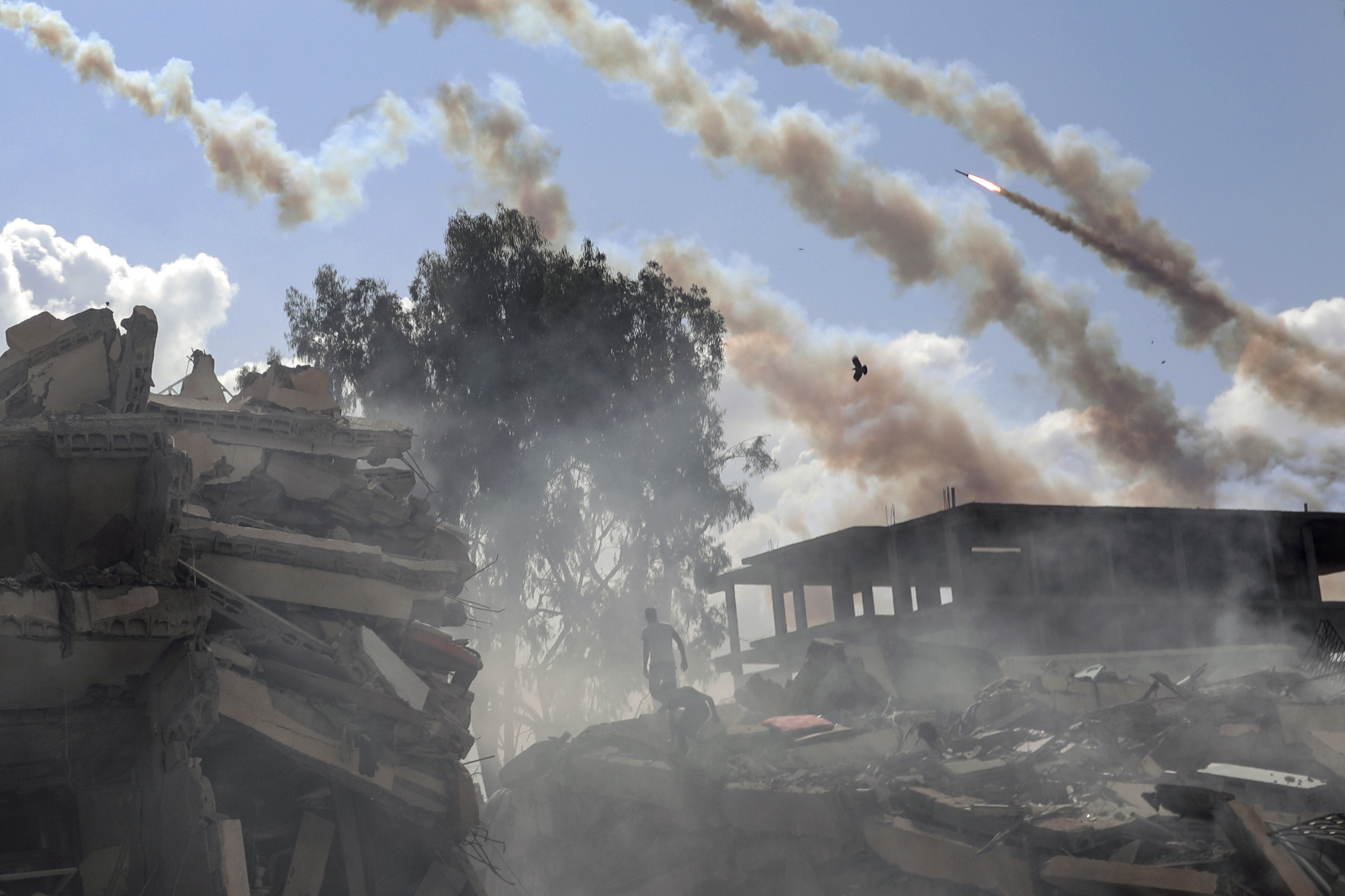 Rockets are fired from the Gaza Strip toward Israel over destroyed buildings following Israeli airstrikes on Gaza City, central Gaza Strip, Thursday, Oct. 19, 2023.