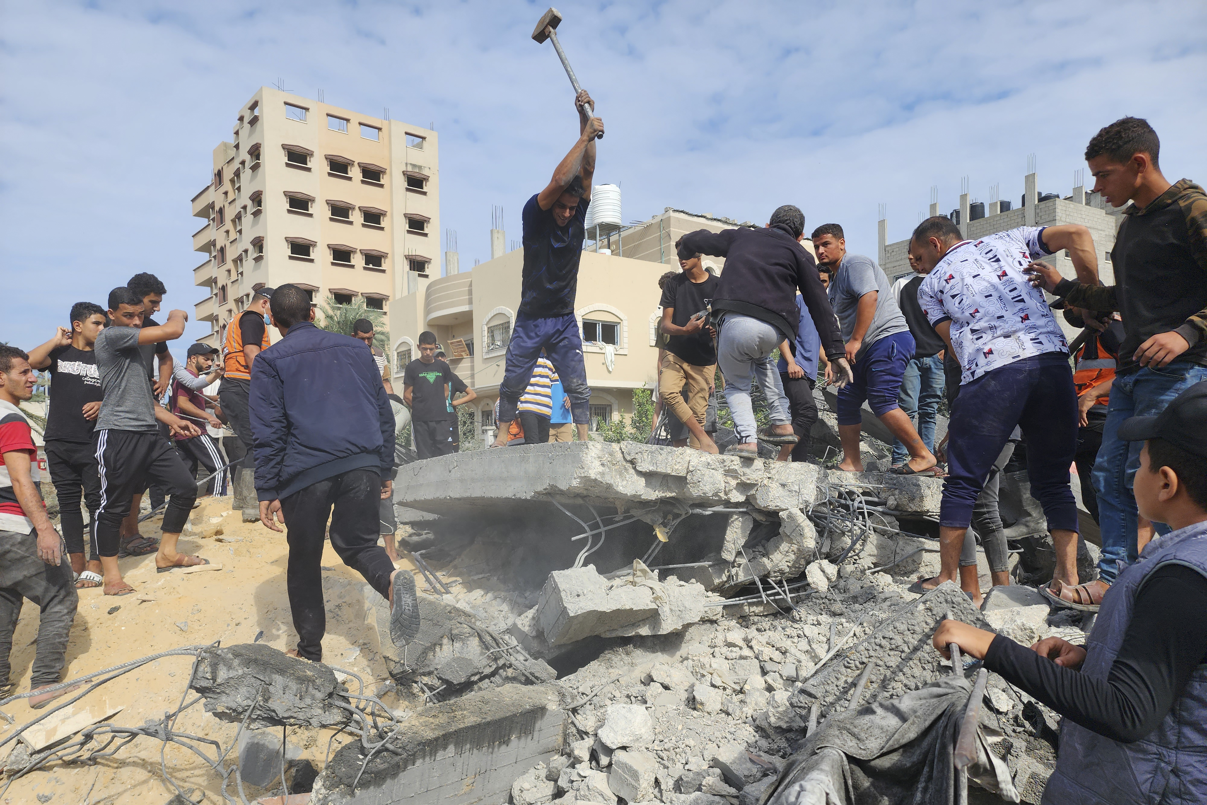 Palestinians look for survivors in buildings destroyed by Israeli airstrikes in Deir el-Balah, southern Gaza Strip, Tuesday, Oct. 17, 2023.